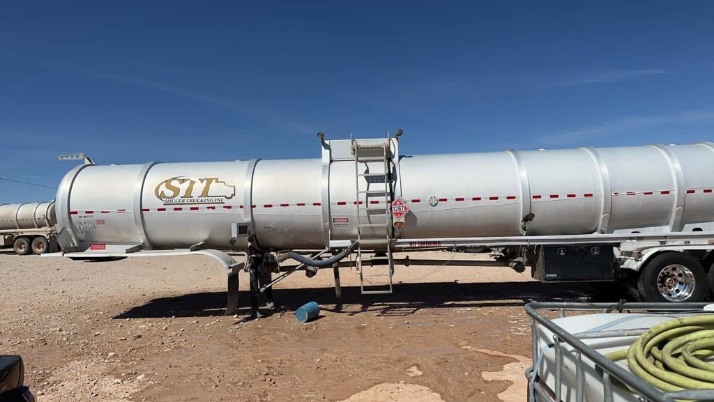 Silver tanker trailer on a job site with pressure washing equipment nearby